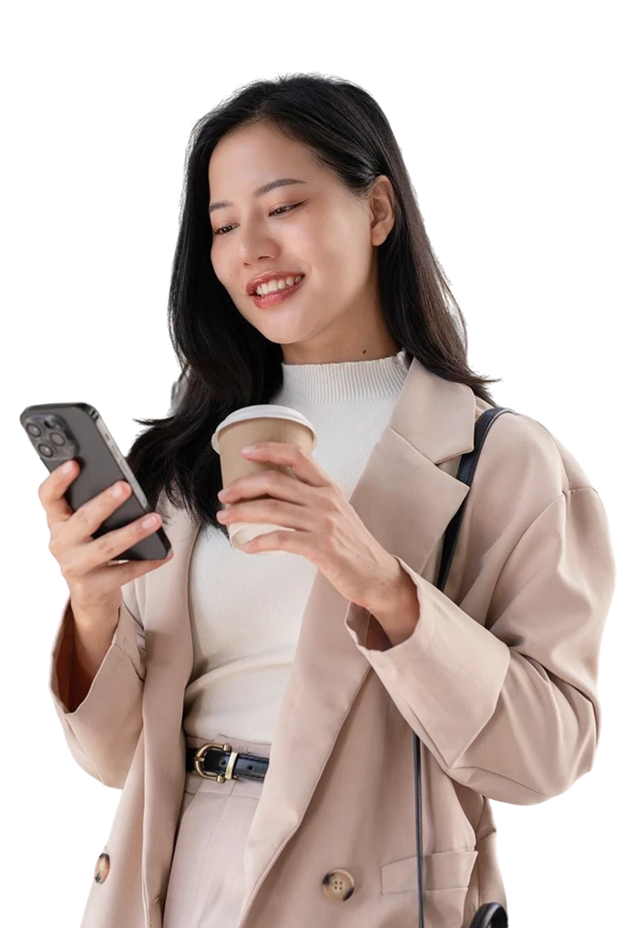 Smiling young woman holding a phone and a coffee cup